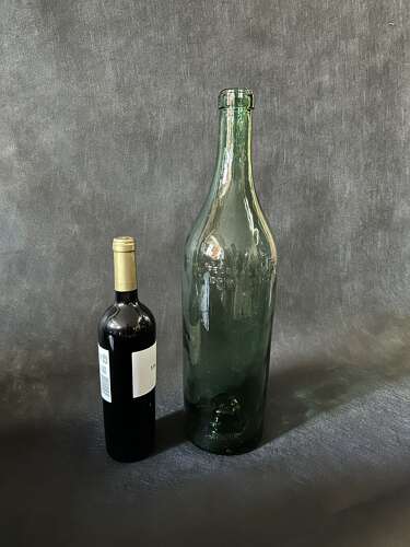 A WALL OF LARGE GREEN COGNAC BOTTLES, FRANCE C1935